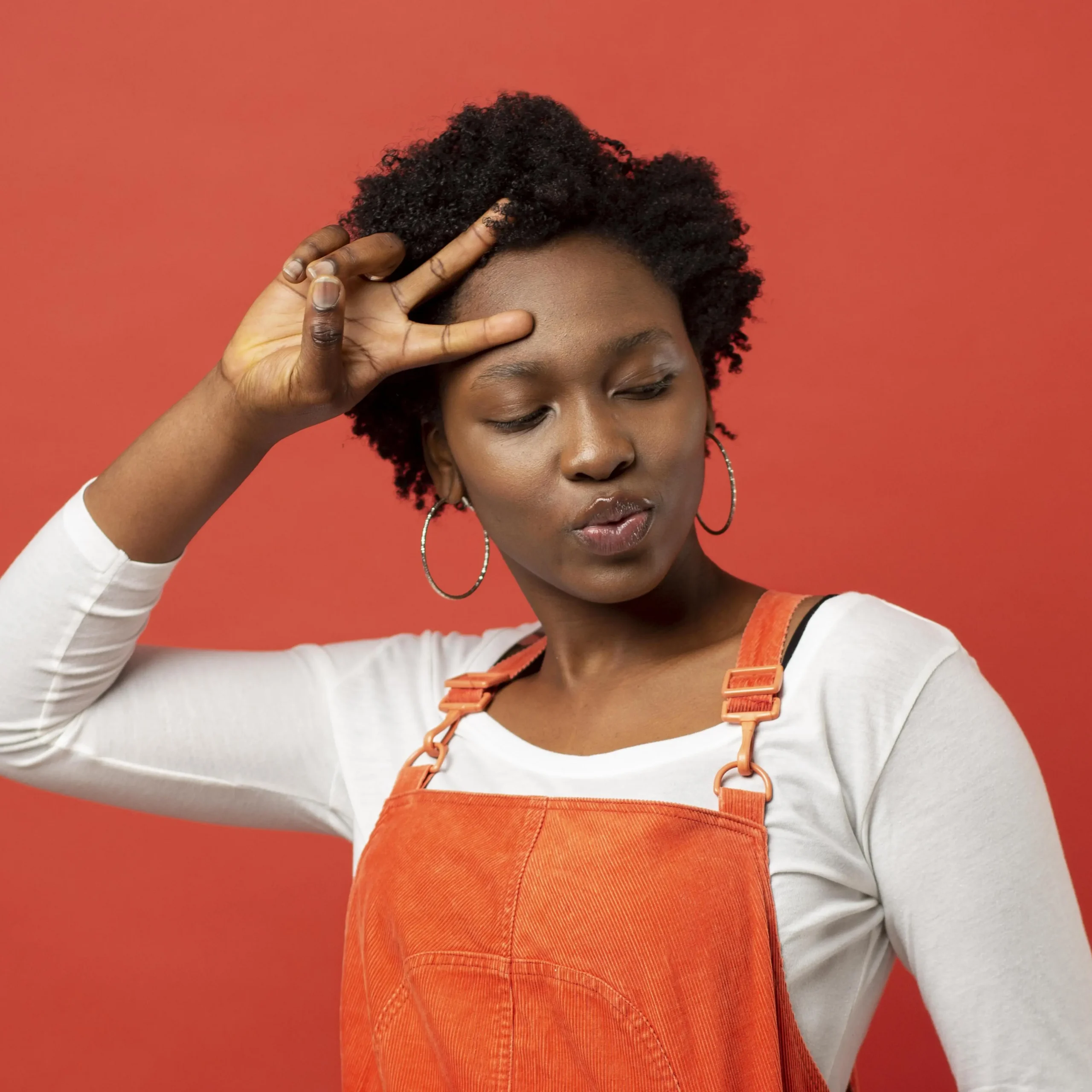 Jeune femme expressive en salopette orange faisant un geste de la main – image dynamique pour illustrer une équipe motivée